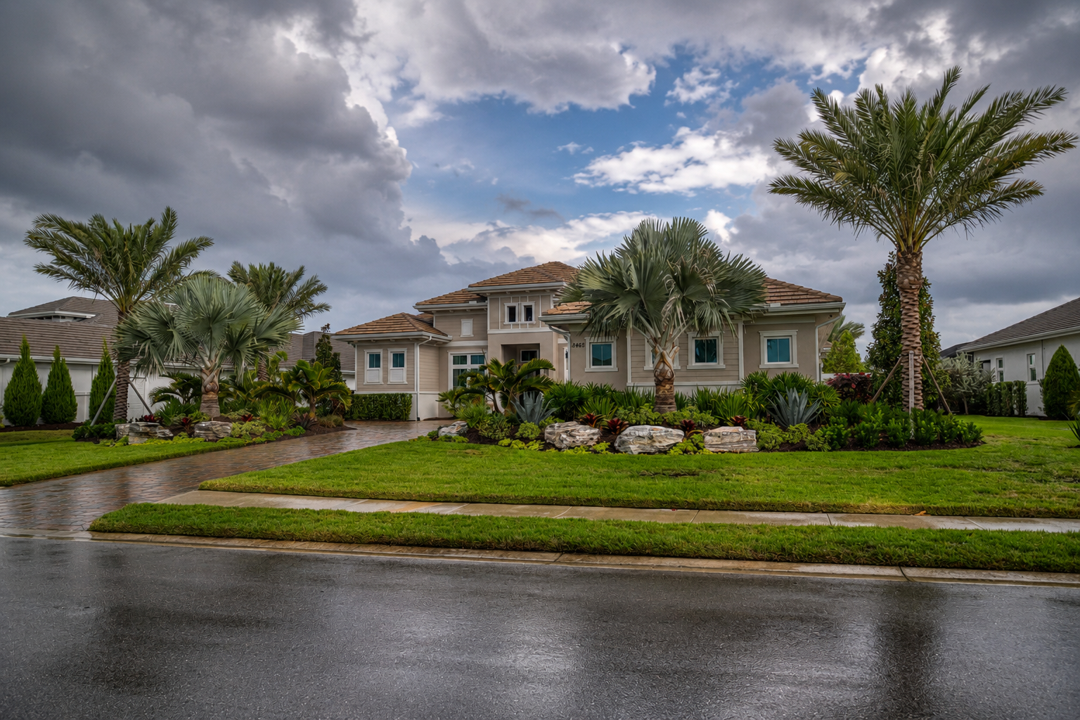 Florida landscape drainage around a luxury home with palms, lawn, and tropical planting beds after summer rain.